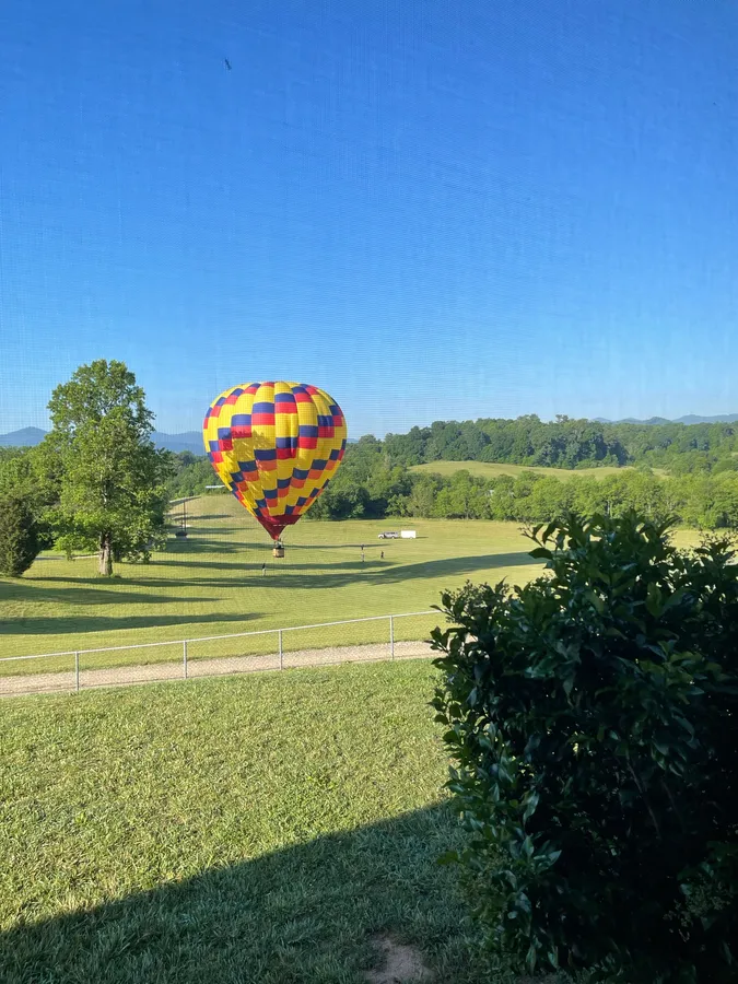 A hot air balloon landed in a Candler field with the chase crew walking out to it