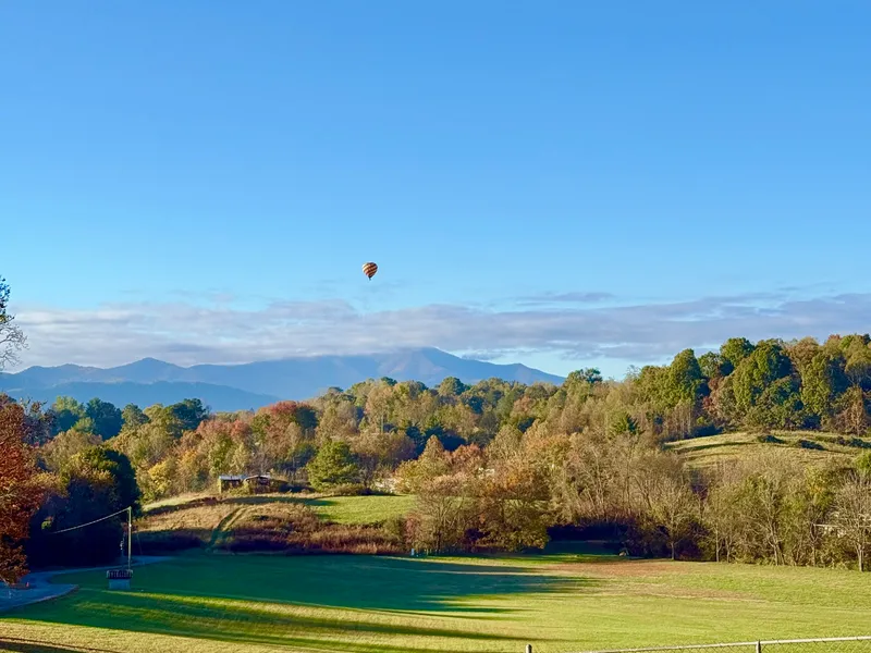 A hot air balloon high over the Hominy Valley in Candler at sunrise, fall color on the ridges